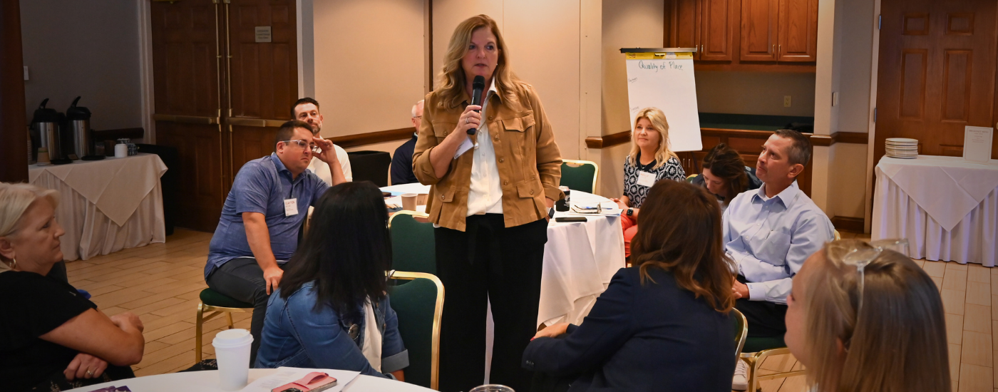 Woman with microphone speaking to peers