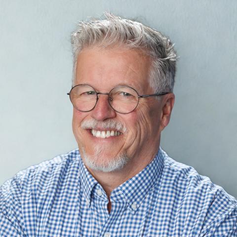 Caucasian man with glasses and gray hair.