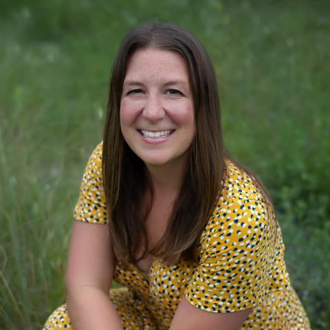 Caucasian woman with long brown hair knealing in grass
