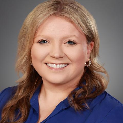 Caucasian woman with medium blond hair and blue shirt.