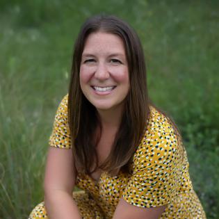 Caucasian woman with long brown hair knealing in grass