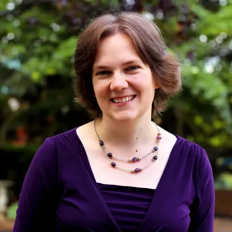 Caucasian woman with brown hair and purple shirt.