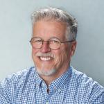 Caucasian man with glasses and gray hair.