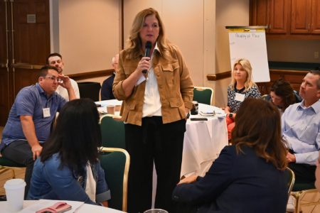 Woman with microphone speaking to peers