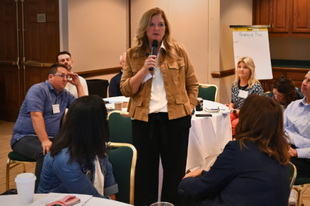 Woman with microphone speaking to peers