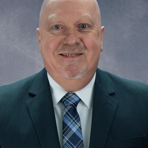 Caucasian man with navy suit jacket and tie.