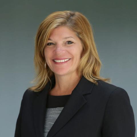 Caucasian woman with medium blond hair and navy jacket