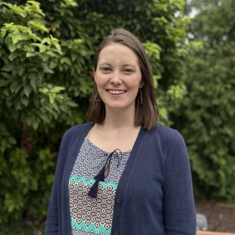 Caucasian woman with shoulder length brown hair and blue cardigan.