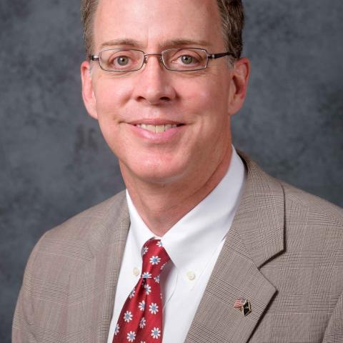 David Lasater, middle-aged man with a tan suit and red tie