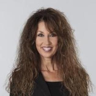 Caucasian woman with long curly brown hair wearing a black top