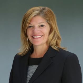 Caucasian woman with medium blond hair and navy jacket