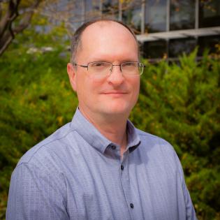 Caucasian man with glasses and blue button down