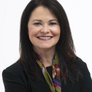 Smiling female with straight, dark hair, wearing black blazer and colorful scarf